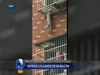 Un nene colgando de un balcón
