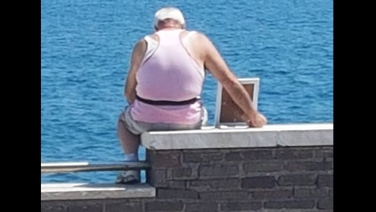 La foto de un hombre que mira al mar con un retrato de su esposa fallecida conmueve a todos en las redes