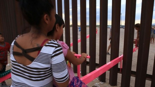 Los niños juegan al “sube y baja” en la frontera de México y EEUU
