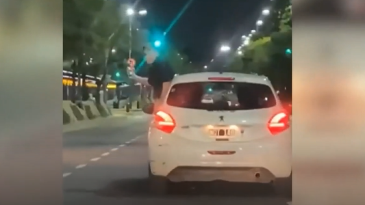 Un joven fue captado en plena 9 de Julio sacando fotos colgado de un auto