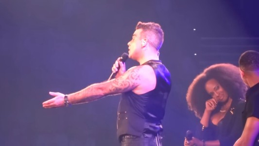Robbie Williams coquetea con una fan en medio de su show y se arrepiente