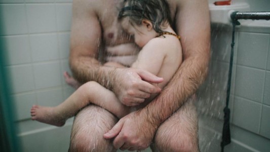 Un padre intentando aliviar a su hijo enfermo en la bañera, la foto censurada