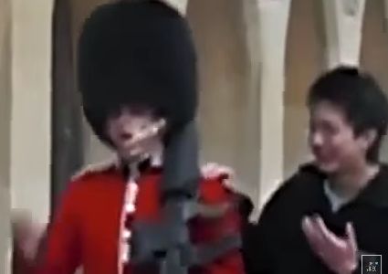 Un guardia real británico apunta con su fusil a un turista, harto de sus burlas
