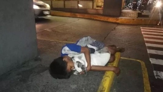 Un nene sin hogar duerme abrazado a su perro en las calles de Filipinas