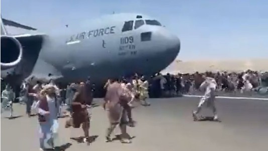 Afganos desesperados intentan huir y subirse a un avión que está despegando